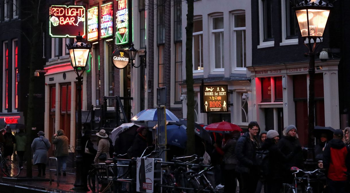 Pessoas caminham pelo distrito da luz vermelha no centro de Amsterdã, Holanda